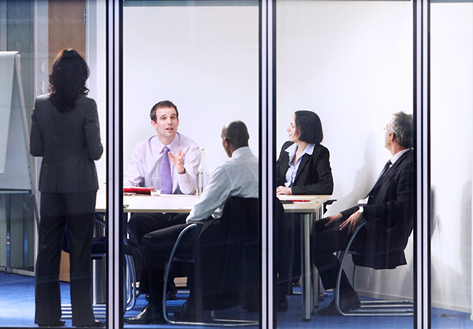 Business people sitting around a table talking while one person is standing up